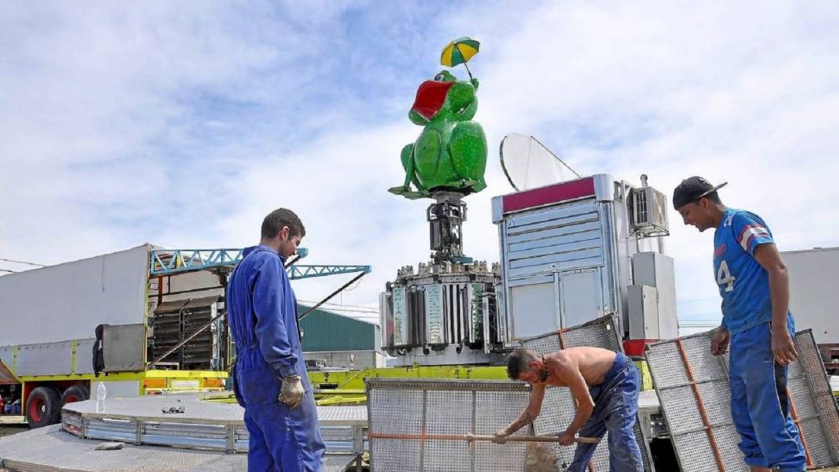 Tres operarios instalan uno de los carruseles en el recinto ferial dedicado a los más pequeños-Santiago G. del Campo