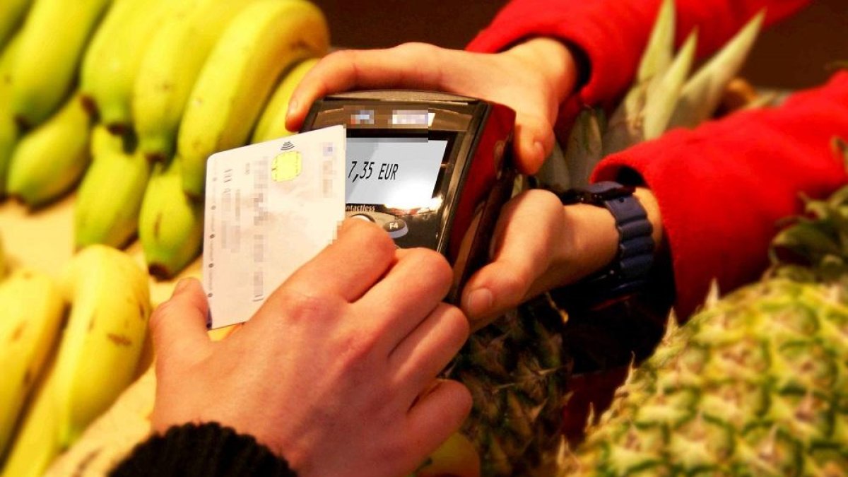 Una persona paga una compra de productos de alimentación con una tarjeta de crédito.