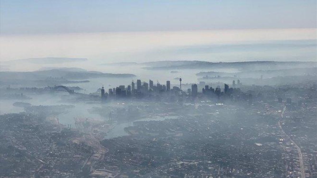 Imagen aérea de la ciudad de Sídney cubierta por una densa nube de humo blanco, este martes.-NEIL BENNETT (DPA)
