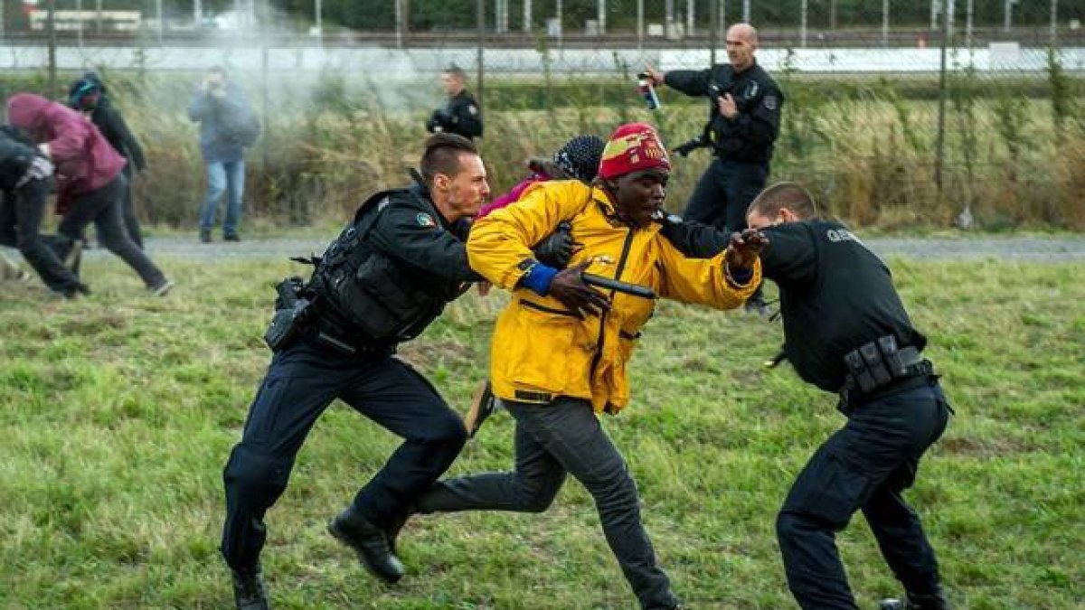 Policías franceses intentan parar a los inmigrantes que buscan colarse al Eurotúnel en Calais este miércoles.-Foto:   AFP / PHILIPPE HUGUEN