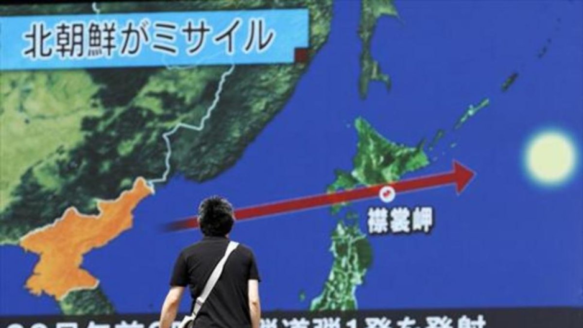 Un viandante observa la trayectoria del misil norcoreano en una pantalla gigante colocada en Tokio (Japón).-EFE / KIMIMASA MAYAMA