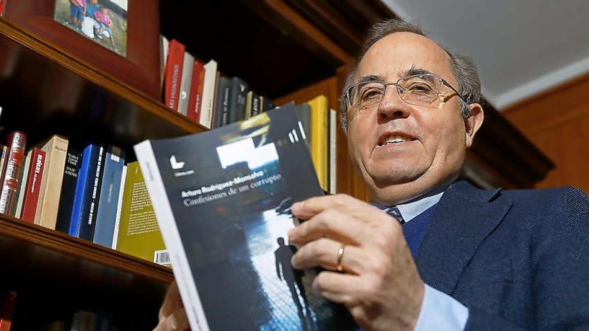 El autor, Arturo Rodríguez–Monsalve, posa con su segundo libro en la biblioteca de su domicilio.-J. M. LOSTAU