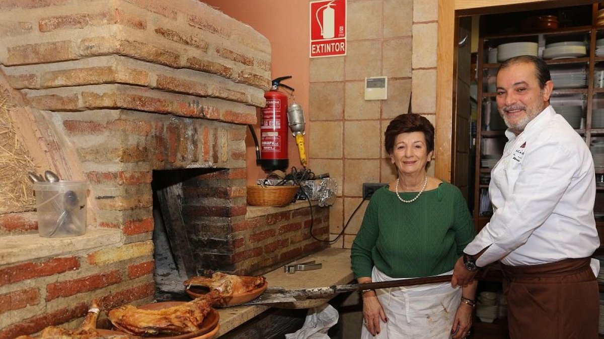 Alberto Sánchez, propietario del restaurante La Encina,de Palencia, saca del horno unos cuartos de lechazo, junto a su madre Ciri González.-MANUEL BRÁGIMO