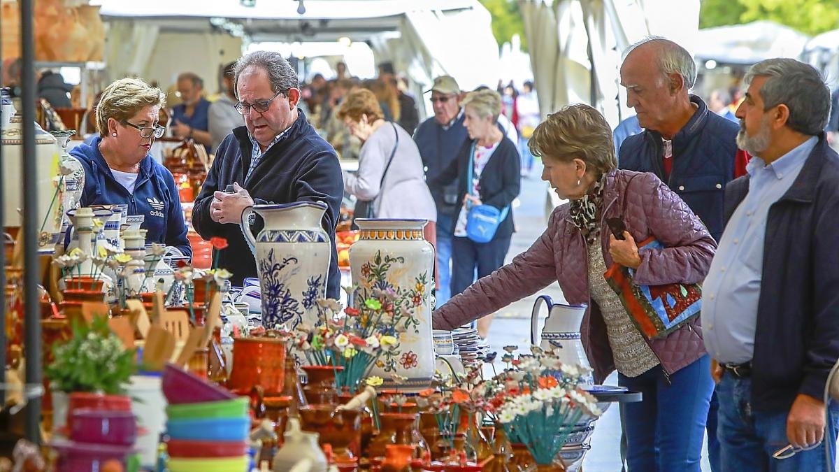 Varias personas contemplan los productos en la Feria de Cerámica y Artesanía de la Acera de Recoletos.