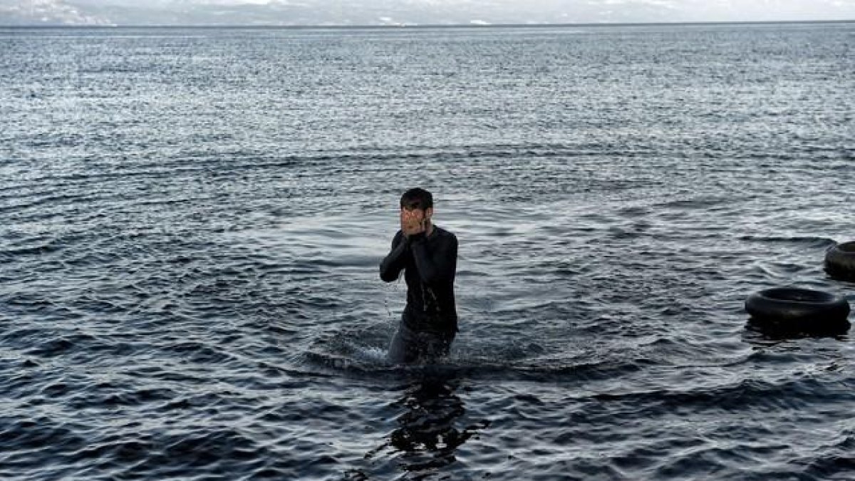 Un refugiado camina entre las aguas tras alcanzar la playa de Lesbos.-AFP / ARIS MESSINIS