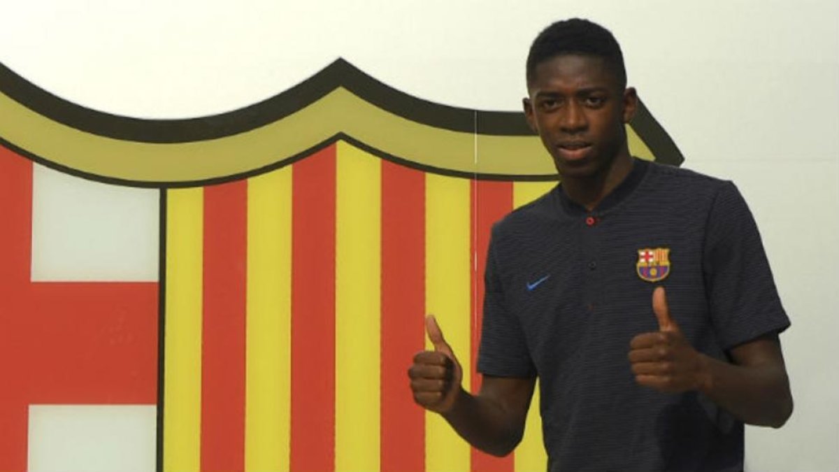 Dembelé posa ante el escudo del Barça en las oficinas del Camp Nou.-AFP / LLUÍS GENÉ
