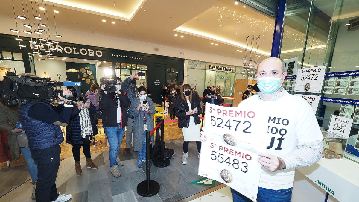 Luis Vázquez, lotero de la administración La Rana de Oro del centro comercial Río Shopping, enseña los carteles del tercer y el quinto premio. | PABLO REQUEJO, PHOTOGENIC