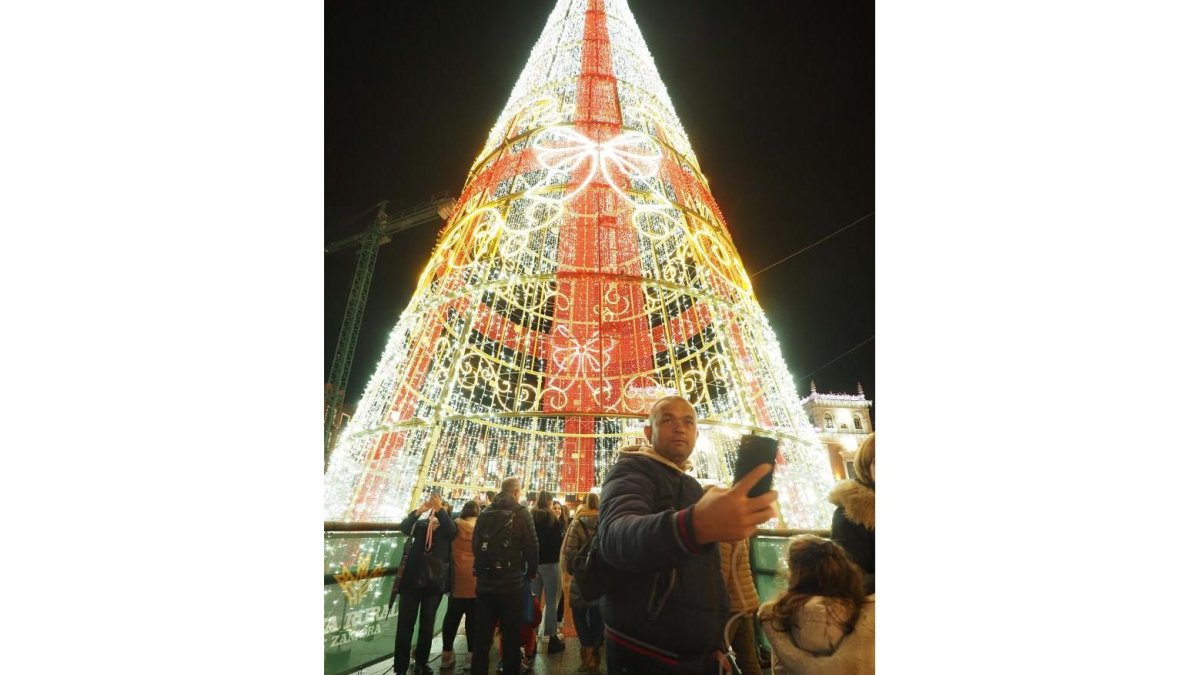 Un varón se fotografía con el árbol de Navidad de la plaza Mayor de Valladolid. PHOTOGENIC