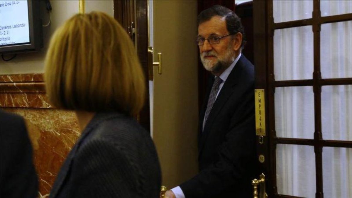 El presidente del Gobierno, Mariano Rajoy, y la ministra de Defensa, María Dolores de Cospedal, en los pasillos del Congreso.-AGUSTIN CATALAN