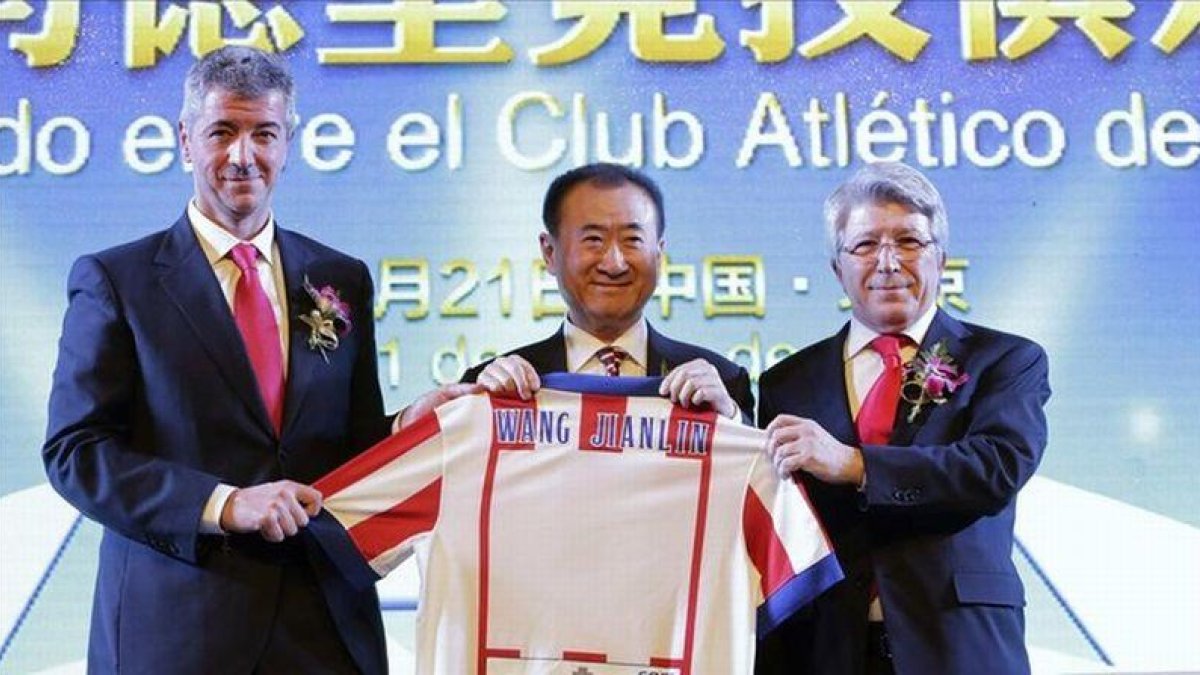 Wang Jianlin, presidente del grupo Wanda, sostiene una camiseta del Atlético de Madrid entre el director general, Miguel Ángel Gil, y el presidente, Enrique Cerezo, tras comprar un 20% del club por 45 millones de euros.-REUTERS / JASON LEE