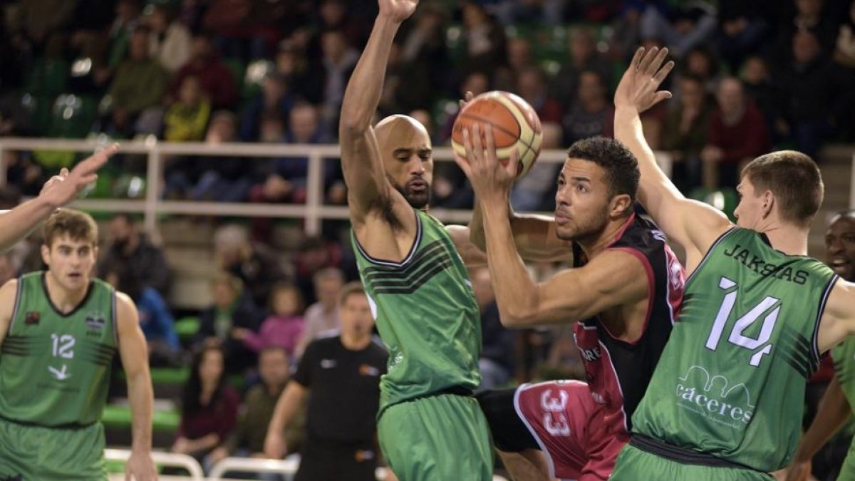 Jito Kok intenta abrirse paso en el poste bajo entre Saunders y Jakstas ayer en el Multiusos de Cáceres.-PHOTO-DEPORTE