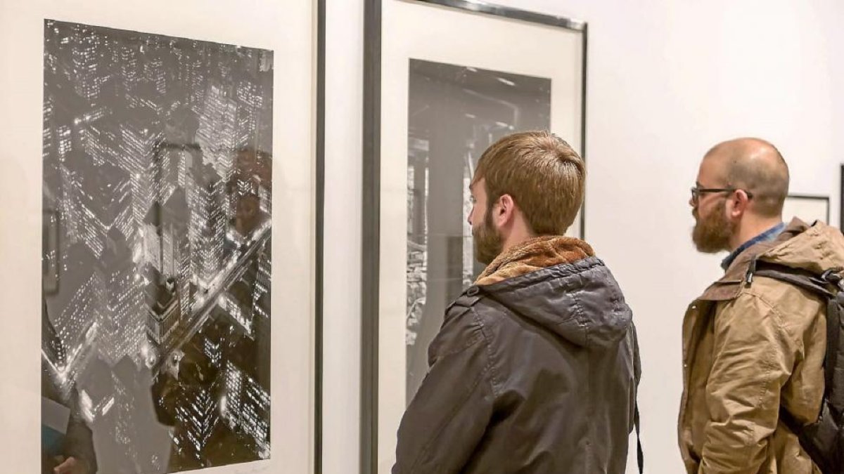 Dos hombres contemplan dos fotografías nocturnas de la serie de Abbott ‘Changing New York’.-Miguel Ángel Santos