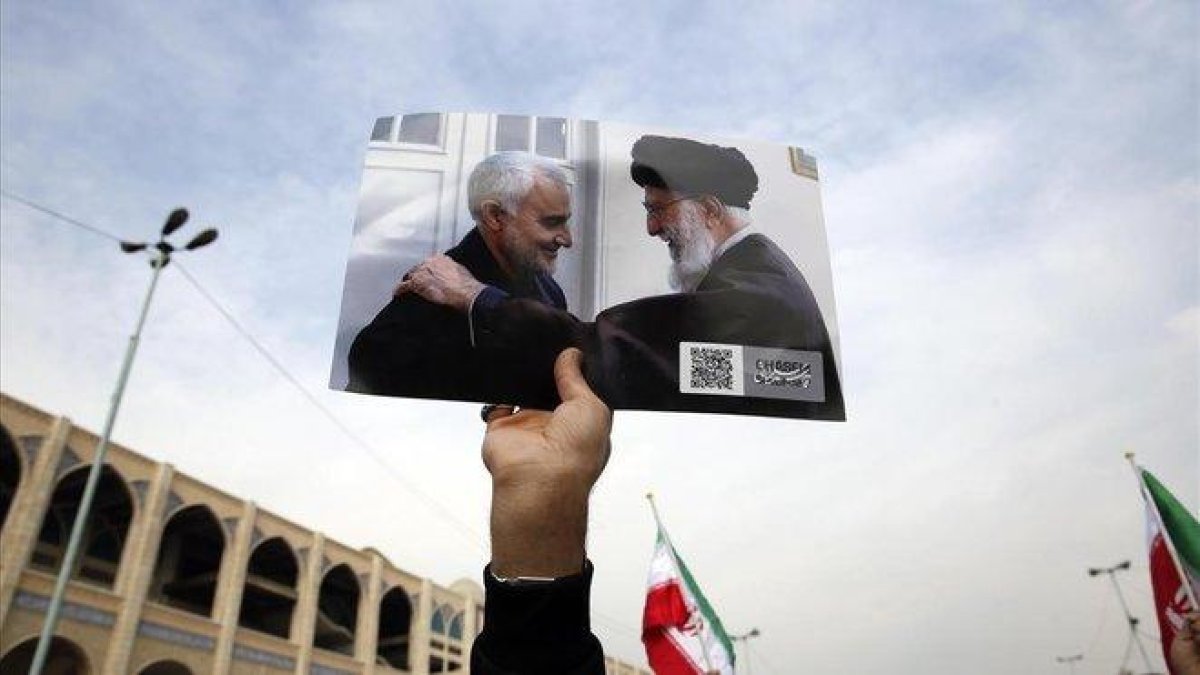 Un manifestante muestra la foto del guía supremo, Alí Jamenei, junto al general Qasim Soleimani.-EFE / ABEDIN THAERKENAREH