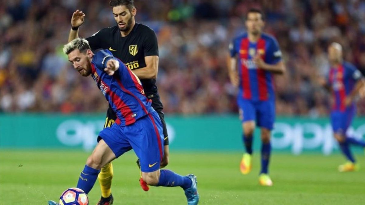 Messi disputa un balón con Carrasco en el Camp Nou antes de lesionarse.-EFE / TONI ALBIR