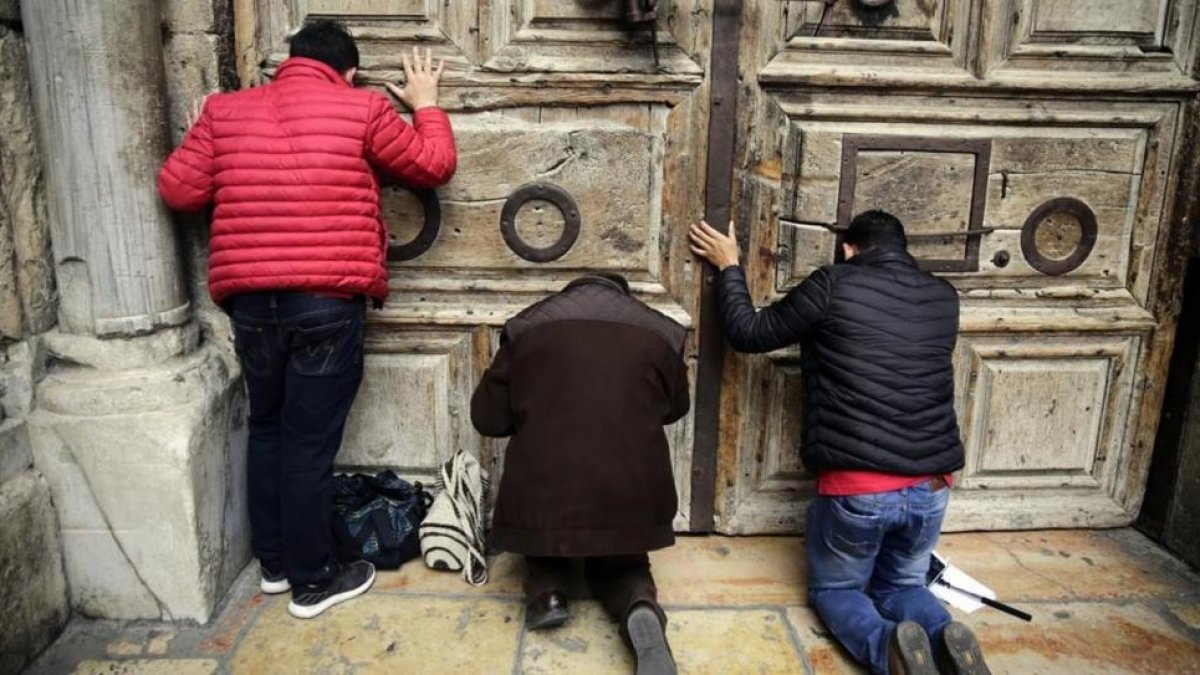 Peregrinos rezan en al puerta del Santo Sepulcro, cerrado.-/ AP / MAHMOUD ILLEAN