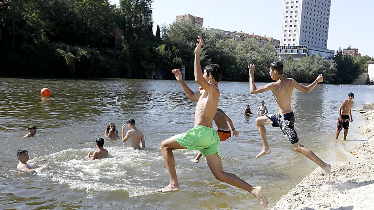 Un grupo de jóvenes se baña en la playa del Pisuerga este martes pese a no ser apta según la Junta. J.M. LOSTAU