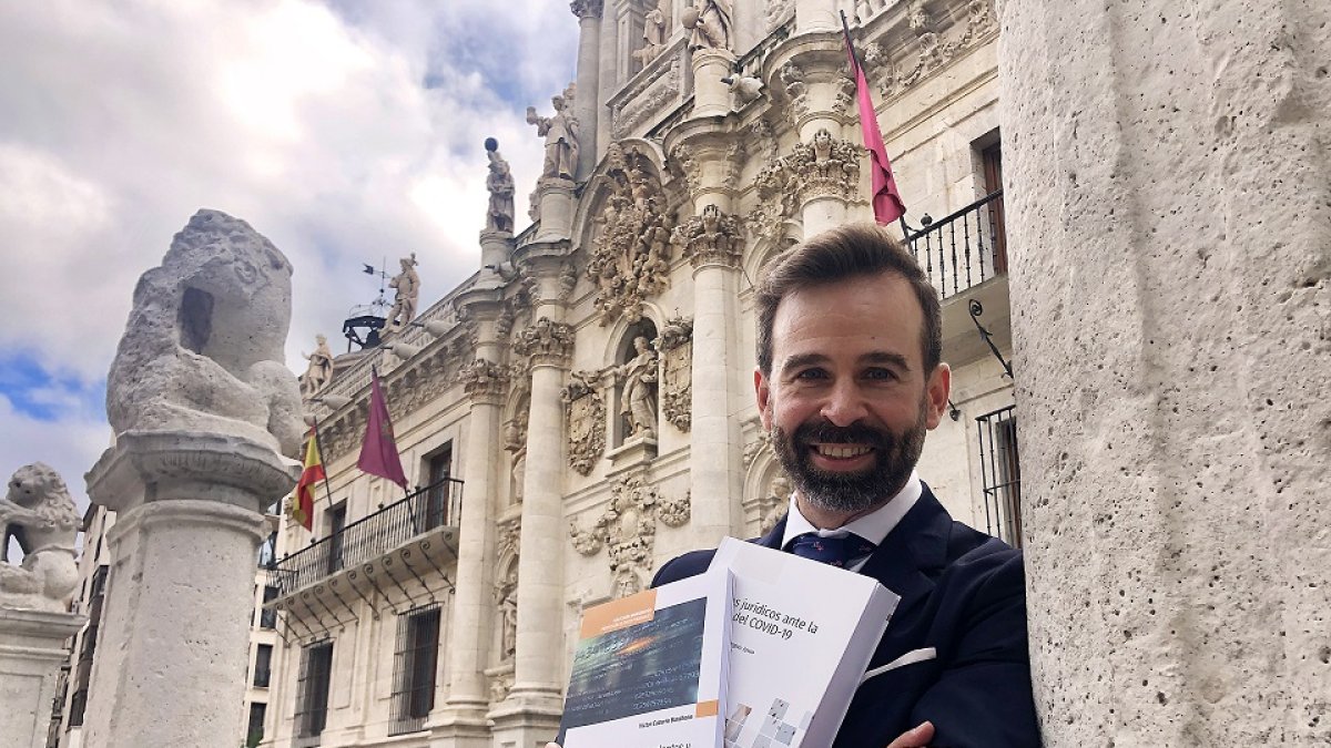 Víctor Cazurro Barahona sujeta sus dos últimos libros sobre la protección de datos frente a la fachada de la Facultad de Derecho de Valladolid../ ARGICOMUNICACIÓN