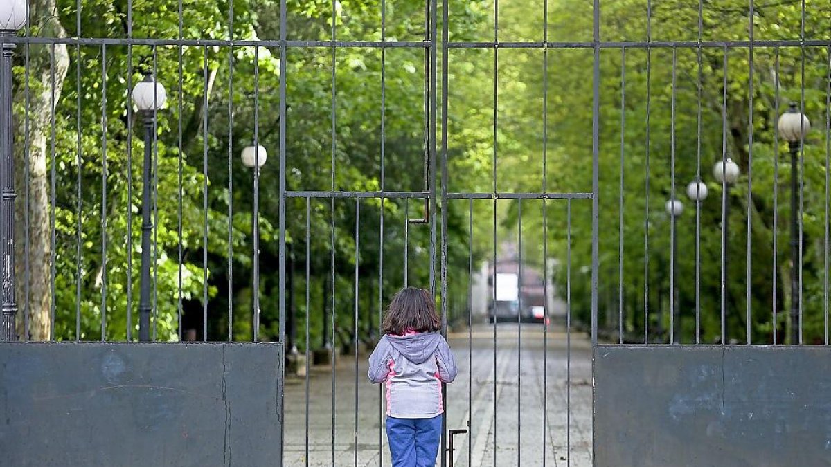 Una niña se asoma por los barrotes de la puerta cerrada del Campo Grande. MIGUEL ÁNGEL SANTOS / PHOTOGENIC