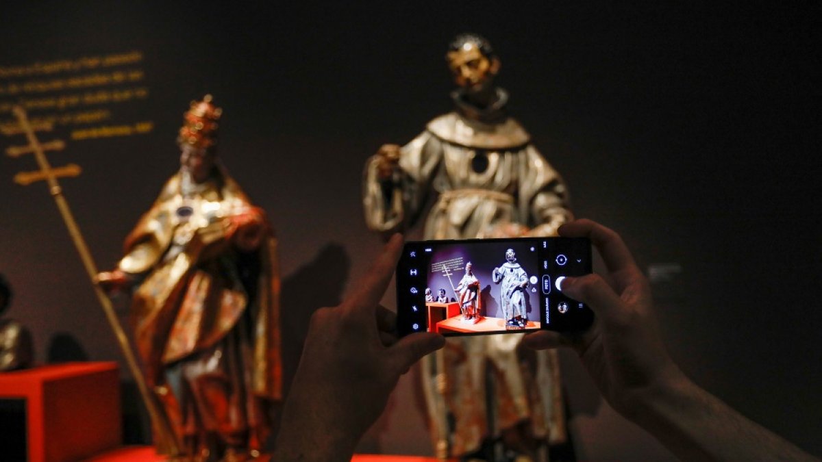 Una persona fotografía dos piezas de la muestra 'Extraña devoción, en Villena. | LOSTAU