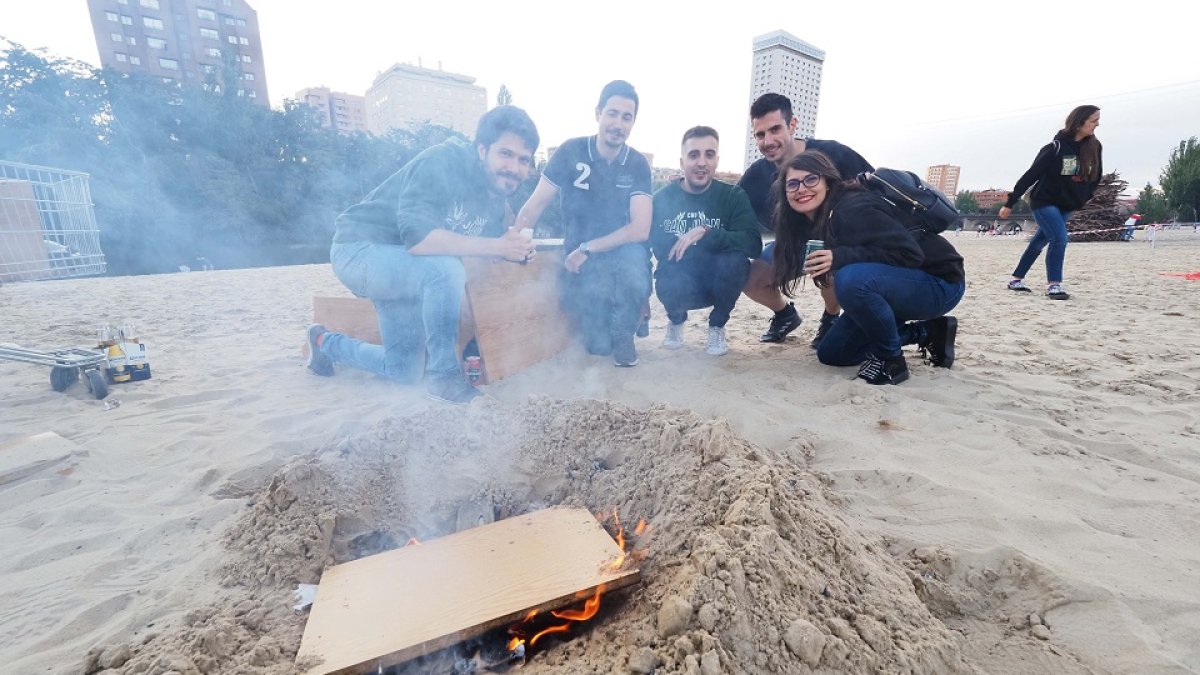 Unos jóvenes preparan la hoguera en la Playa de las Moreras. / PHOTOGENIC