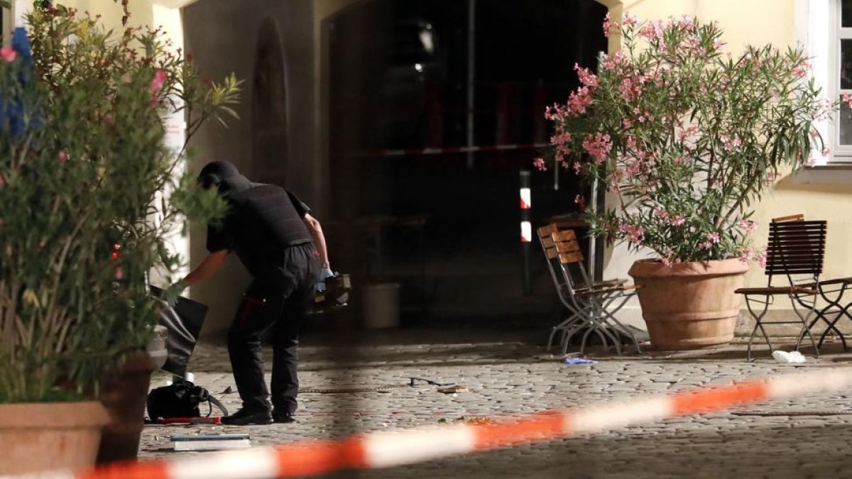 Un agente examina la mochila en la que el autor del ataque llevaba los explosivos, frente a un restaurante de Ansbach (Alemania), este domingo.-AP / MATTHIAS SCHRADER