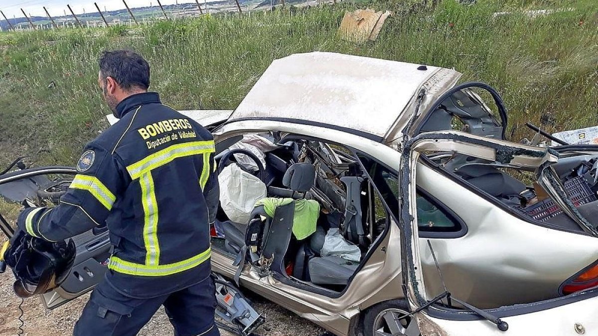 Un bombero examina el turismo siniestrado, con la carrocería cortada a radial para excarcelar el cuerpo de la fallecida.-EL MUNDO