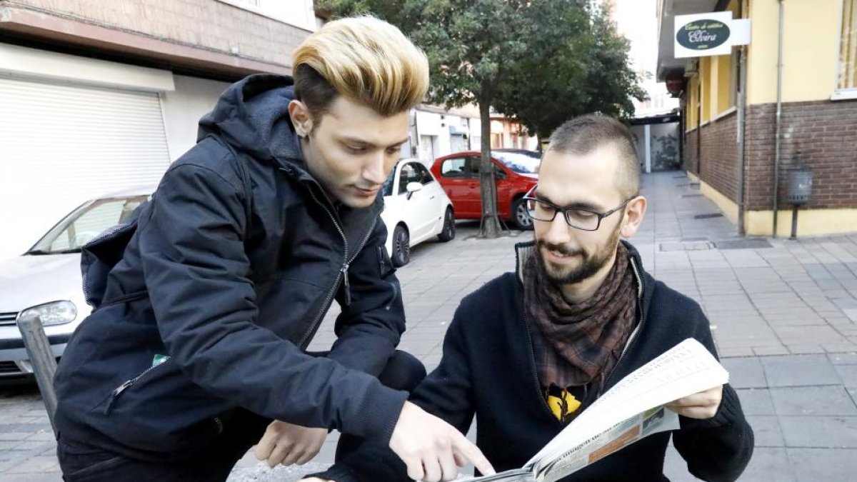 Álvaro y Pablo (sentado) mirando la sección de ofertas de trabajo del periódico.-J.M. LOSTAU