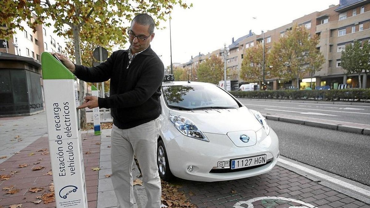 Un hombre utiliza un puesto de recarga de coche eléctrico.-ICAL