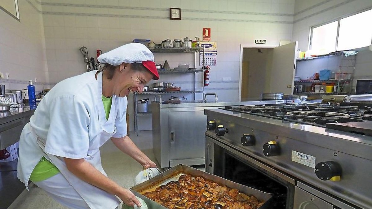 La cocinera Rebeca Mosquera saca del horno el pollo asado con limón y manzana.-MIGUEL ÁNGEL SANTOS (PHOTOGENIC)