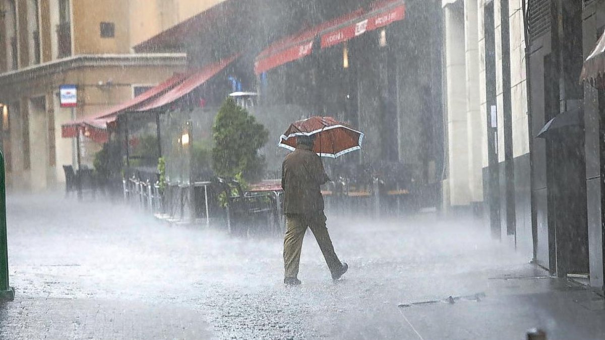 Un hombre pasea con un paraguas durante el temporal de ayer-J.M. Lostau