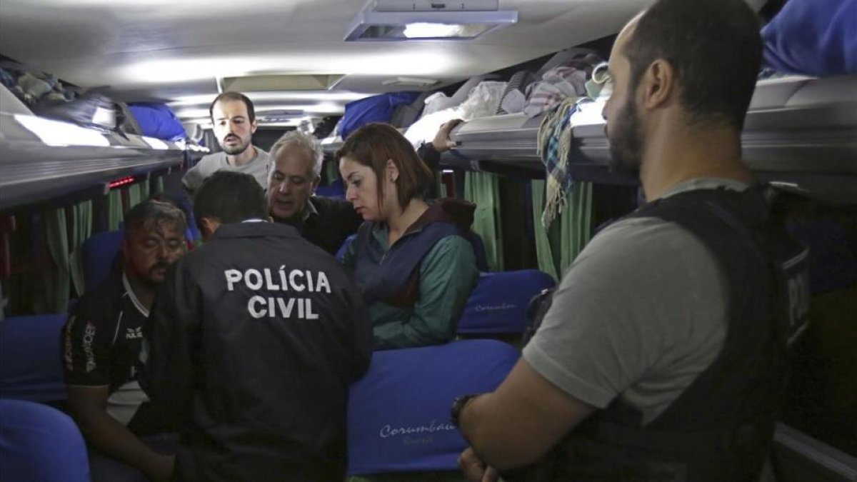 Oficiales de la Policía Civil brasileña en uno de los autobuses de la caravana electoral de Lula, después de ser atacada con disparos este martes en el estado de Paraná.-/ AP / ERALDO PERES