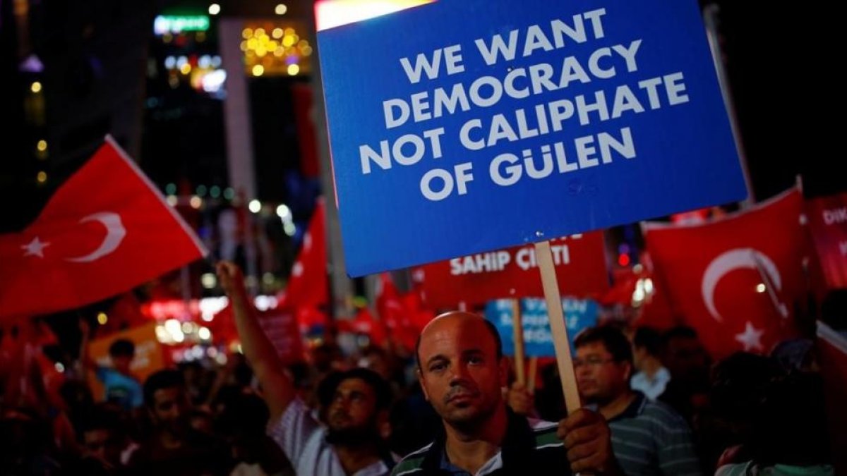 Un hombre sostiene un cartel junto a otros reunidos noche tras noche desde el 15 de julio, día del intento de golpe de Estado, en Ankara, el 27 de julio.-REUTERS / UMIT BEKTAS