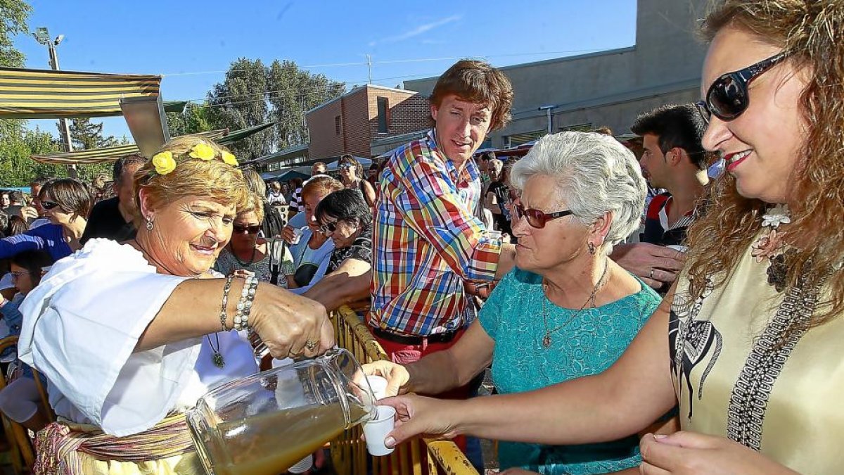 Una ‘lagarera’ sirve el primer mosto del año a algunos visitantes de la Fiesta de la Vendimia, ayer en Serrada.-J.M.LOSTAU