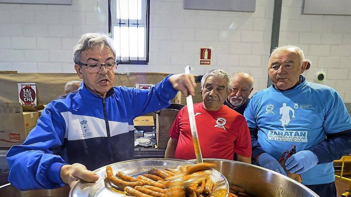 Reparto de las salchichas típicas de Zaratán, ayer en el pabellón deportivo, tras finalizar la Carrera Popular.-MIGUEL ÁNGEL SANTOS / PHOTOGENIC