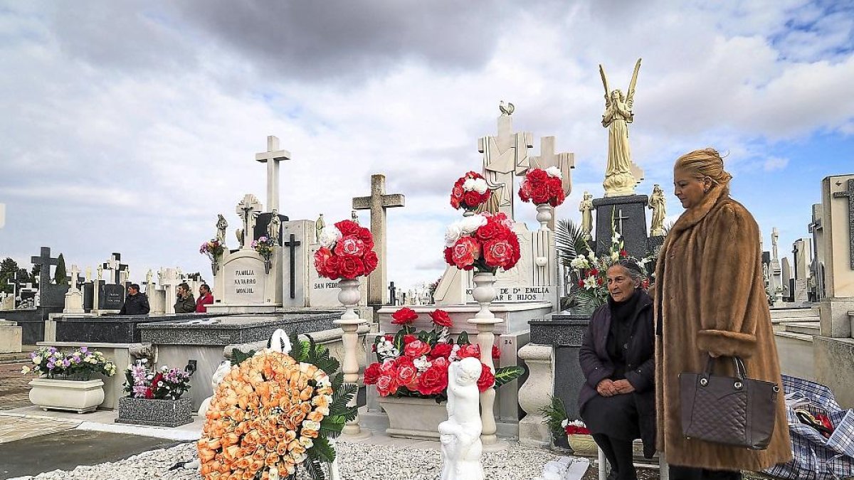 Dos mujeres elevan una oración por sus seres queridos al lado de su tumba.-M.Á. SANTOS (PHOTOGENIC)