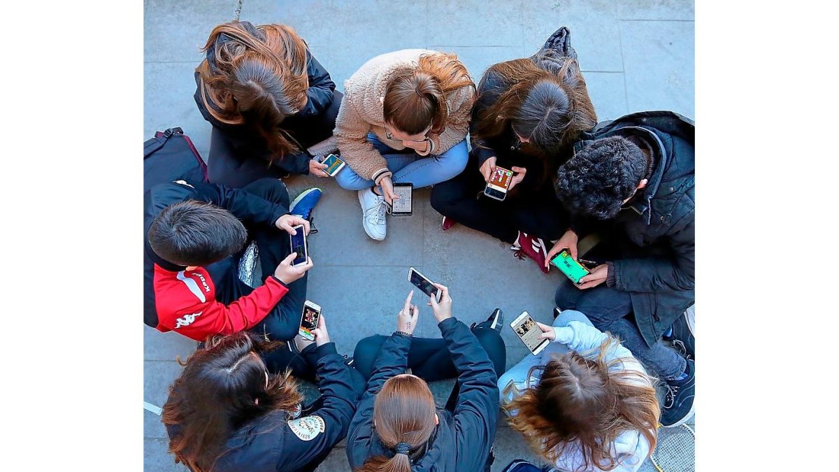 Un grupo de adolescentes interactúan en círculo con sus teléfonos digitales a través de juegos, redes sociales y mensajería. MIGUEL ÁNGEL SANTOS / PHOTOGENIC