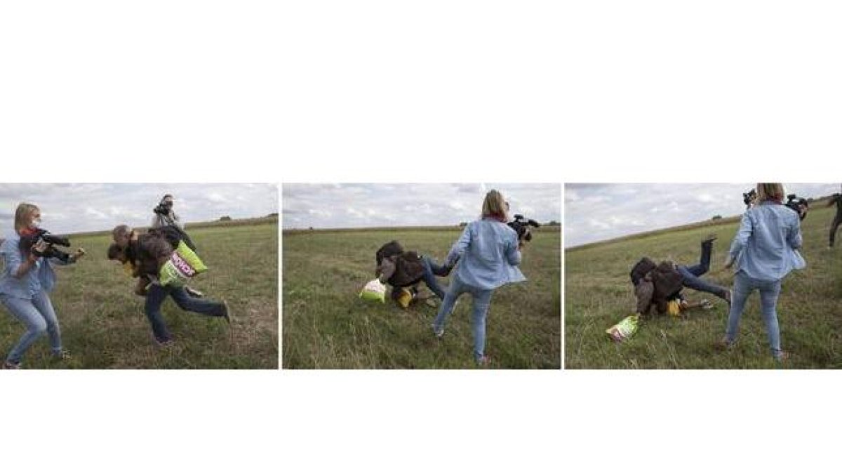 Petra Laszlo le hace la zancadilla a un padre que lleva en brazos a su hijo y una bolsa con sus pertenencias, en Roszke (Hungría).-MARKO DJURICA / REUTERS