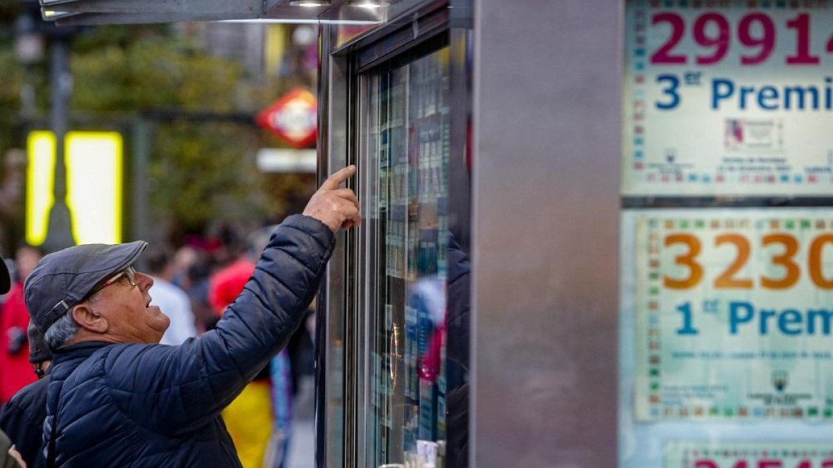 Un hombre señala el décimo de Lotería de Navidad que quiere comprar en una Administración en la plaza de Puerta del Sol, en Madrid (España), a 18 de noviembre de 2019.-EUROPA PRESS