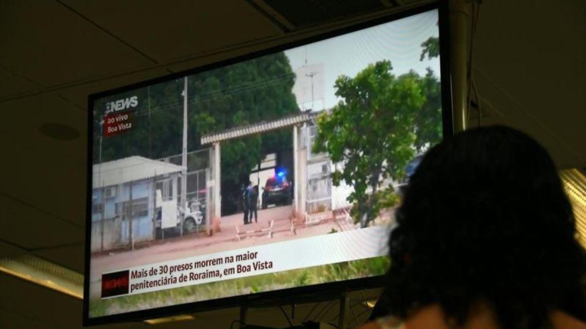 Una mujer sigue la noticia de la masacre en la prisión de Brasil a través de la televisión.-AFP / VANDERLEI ALMEIDA