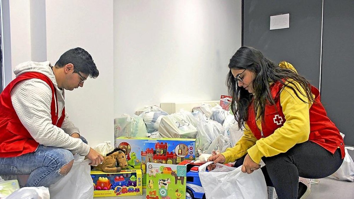 Dos voluntarios de Cruz Roja distribuyen juguetes en distintos lotes antes de proceder a la entrega.-E. M.