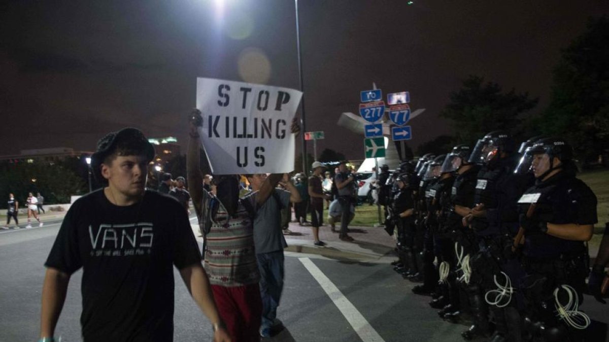 Manifestantes pasean con pancartas ante el cordón policial, esta madrugada en Charlotte.-AFP / NICHOLAS KAMM