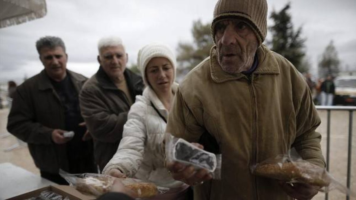 Ciudadanos griegos hacen cola para recibir alimentos con motivo de la celebración del 'Lunes Limpio', este lunes en Atenas.-Foto:   EFE / YANNIS KOLESIDIS