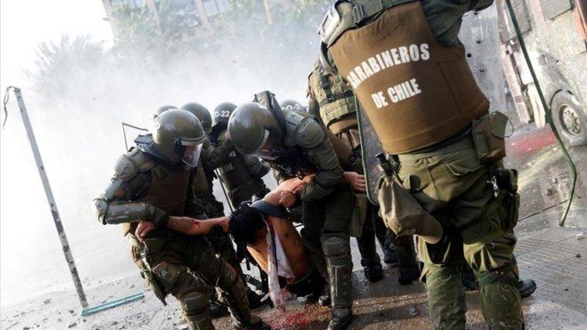 Un herido es trasladado por las fuerzas de seguridad durante las protestas en Santiago.-