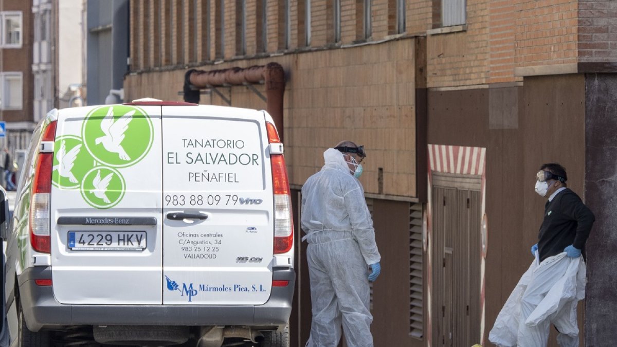 Dos trabajadores de una funeraria se equipan a las puertas del Hospital Clínico. MIGUEL ÁNGEL SANTOS (PHOTOGENIC)