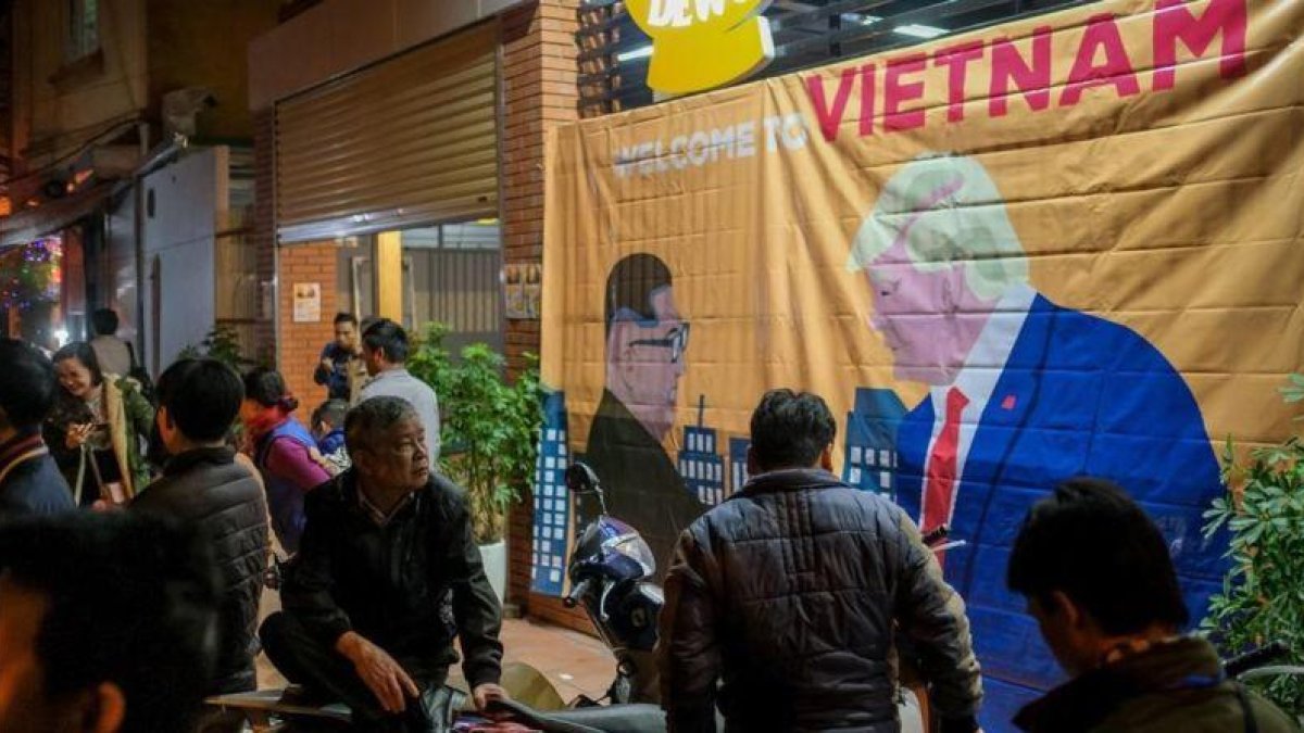 Ciudadanos de Hanói pasan ante un cartel con las imágenes de Kim y Trump horas antes de su encuentro.-LINH PHAM (GETTY IMAGES)