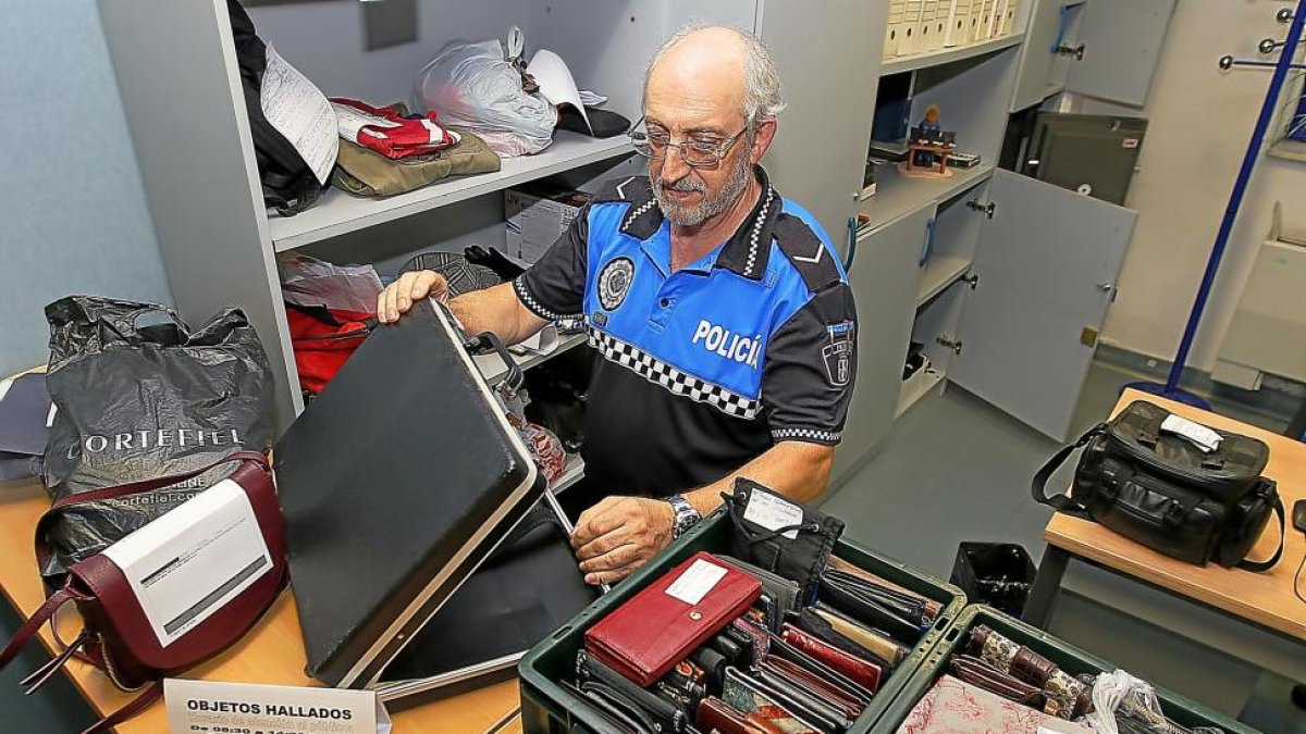 Un agente de la Policía Municipal muestra un ordenador perdido además de prendas de vestir y carteras.-J. M. LOSTAU