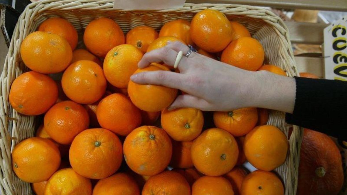 Una persona coge una naranja en un supermercado.-DANNY CAMINAL (ARCHIVO)