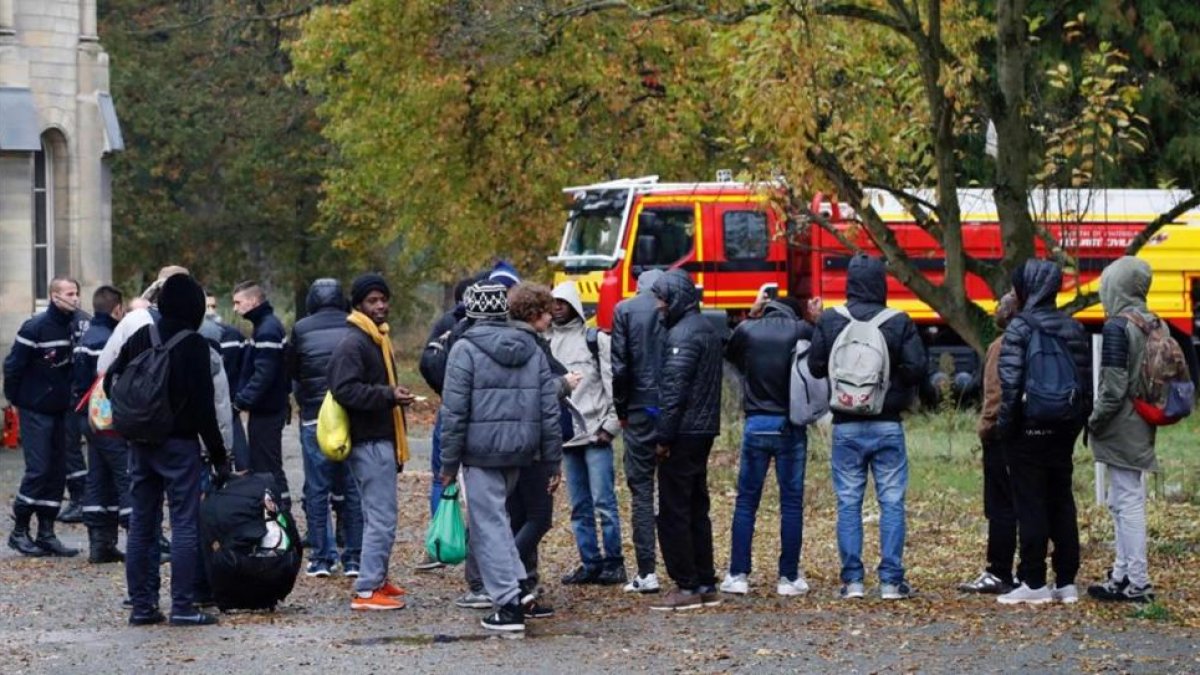 Migrantes acompañados por miembros de la seguridad civil francesa, a su llegada a un nuevo alojamiento en Sarcelles, en el norte de París, este viernes.-AFP / FRANÇOIS GUILLOT