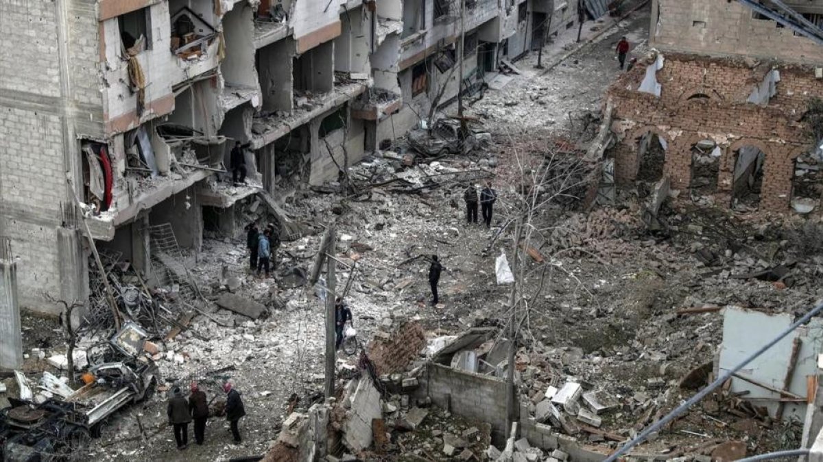 Vecinos inspeccionan los edificios en ruinas tras varios bombardeos el día anterior en Duma, feudo rebelde de Guta Oriental (Siria), el 22 de febrero.-/ EFE / MOHAMMED BADRA