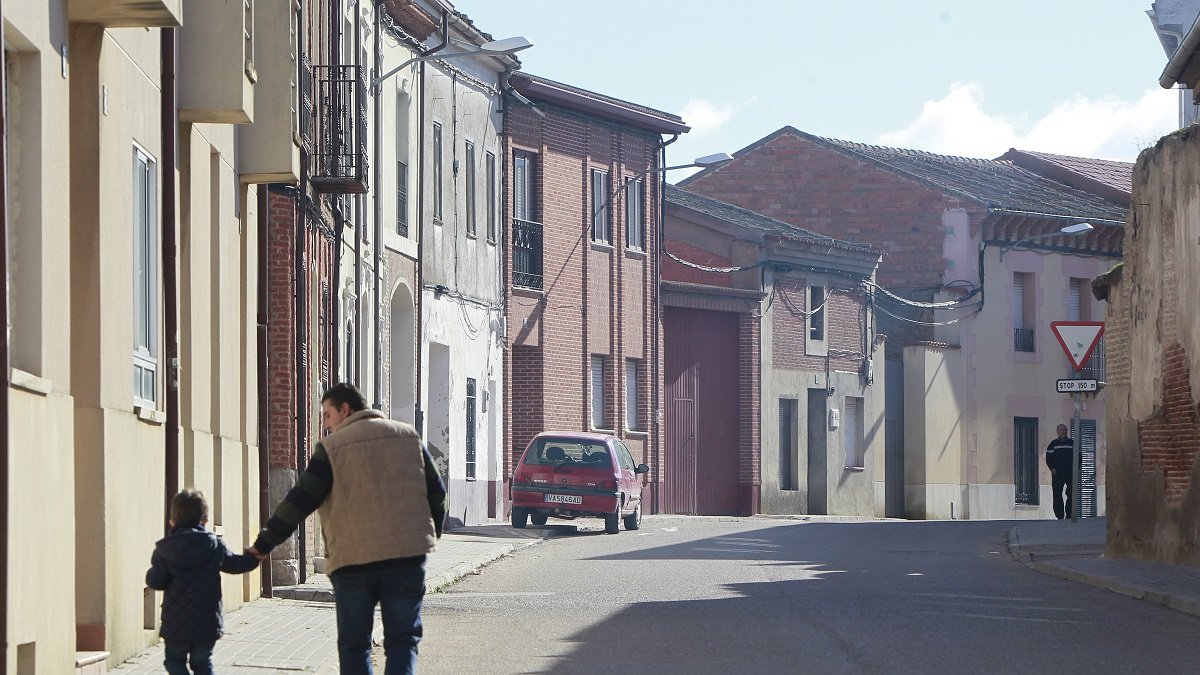 Un niño camina cogido de la mano de su padre por las calles de un pueblo de Valladolid, en una imagen de archivo.- J.M. LOSTAU